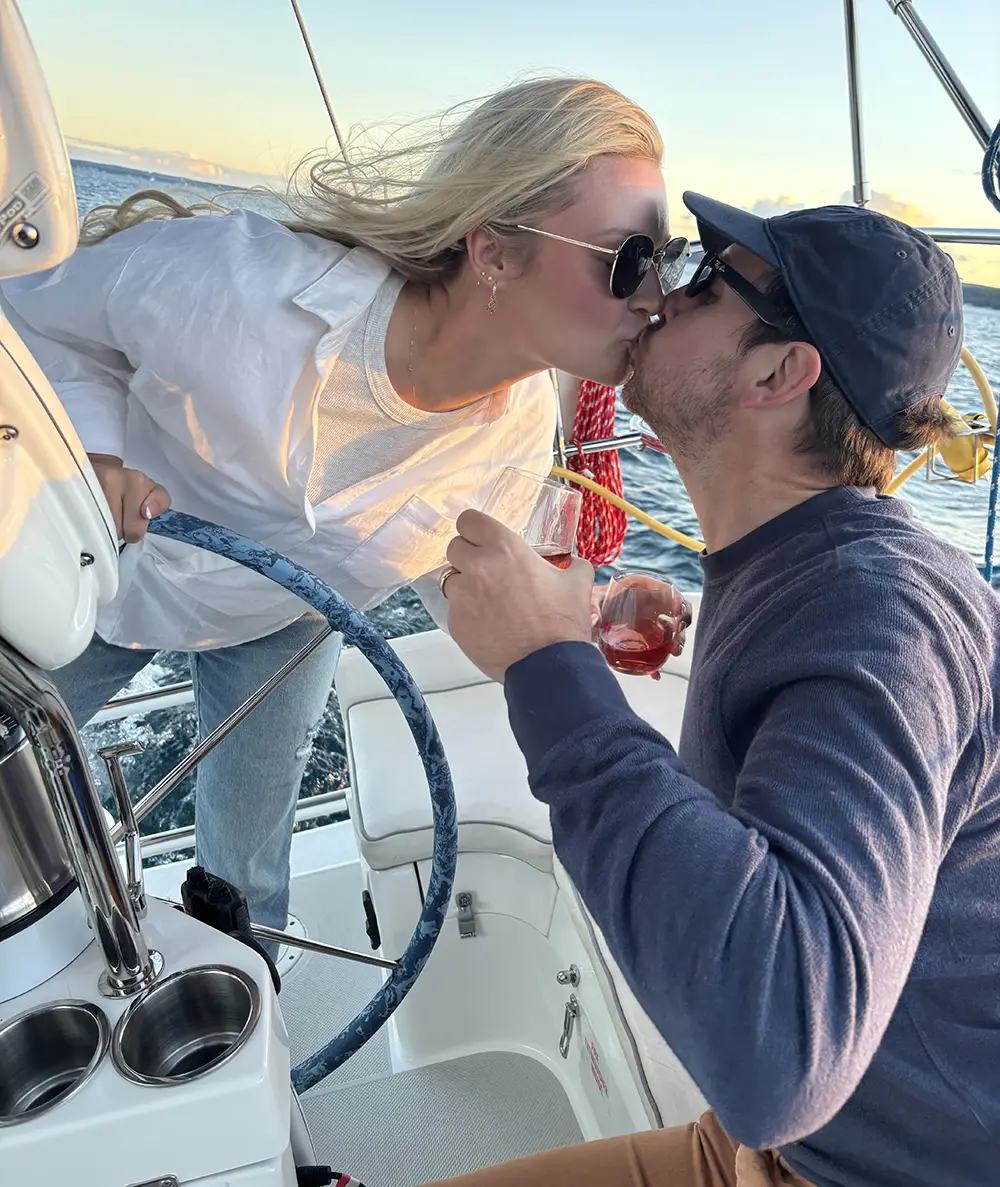 A newly engaged couple share a kiss aboard a summer cruise on the Impulse on Traverse Bay in Traverse City Michigan
