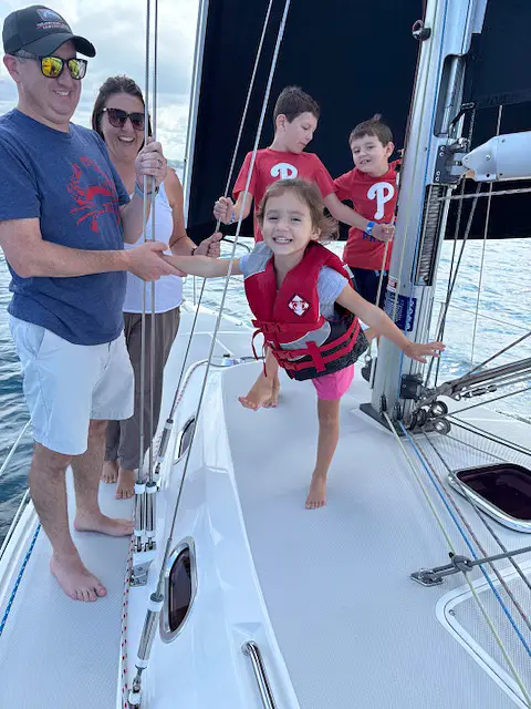 Young child enjoys herself with her brothers and parents on the Impulse while sailing on Grand Traverse Bay
